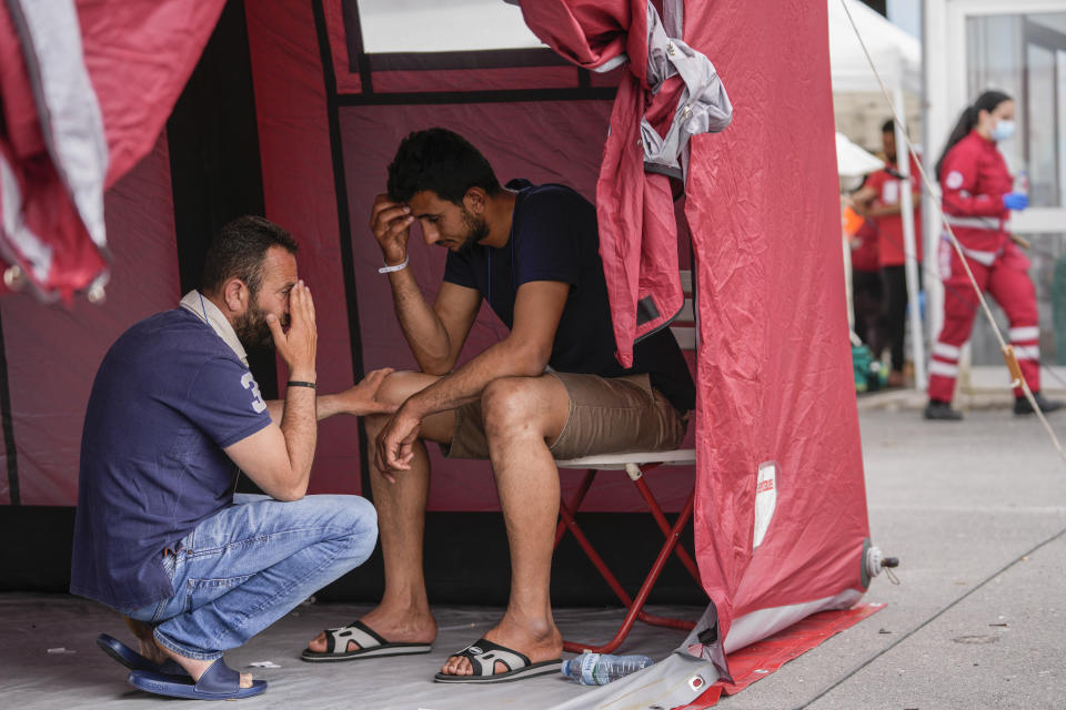 Survivors of a shipwreck react outside a warehouse at the port in Kalamata town, about 240 kilometers (150miles) southwest of Athens, on Thursday, June 15, 2023. A fishing boat crammed to the gunwales with migrants trying to reach Europe capsized and sank Wednesday June 14 off the coast of Greece, authorities said, leaving at least 79 dead and many more missing in one of the worst disasters of its kind this year. (AP Photo/Thanassis Stavrakis)