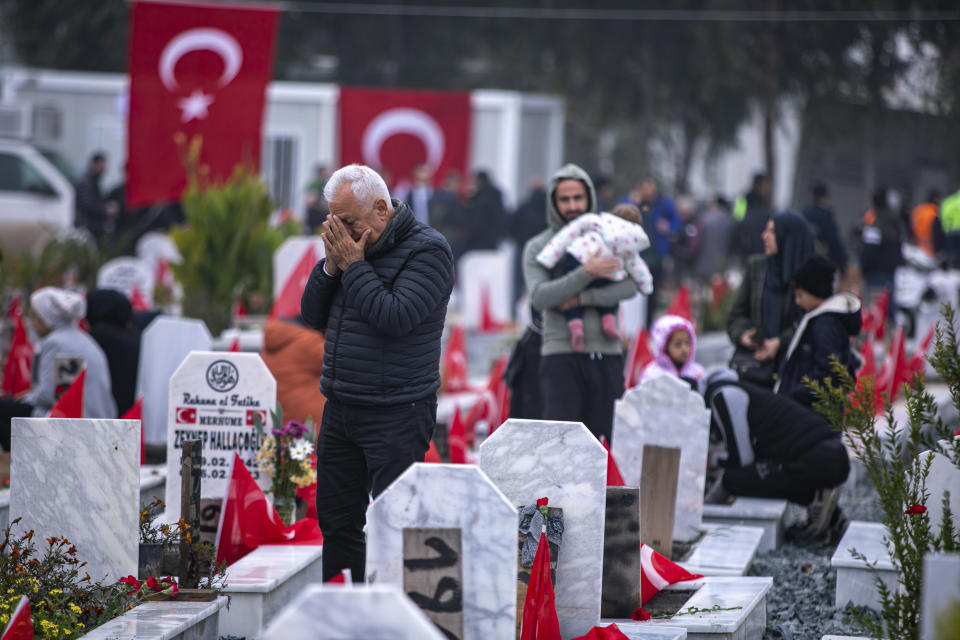 People visit graves in a cemetery where some of the victims of the earthquake in Feb. 2023 are buried in Antakya, southern Turkey, Tuesday, Feb. 6, 2024. Millions of people across Turkey on Tuesday mourned the loss of more than 53,000 friends, loved ones and neighbors in the country's catastrophic earthquake a year ago. (AP Photo/Metin Yoksu)
