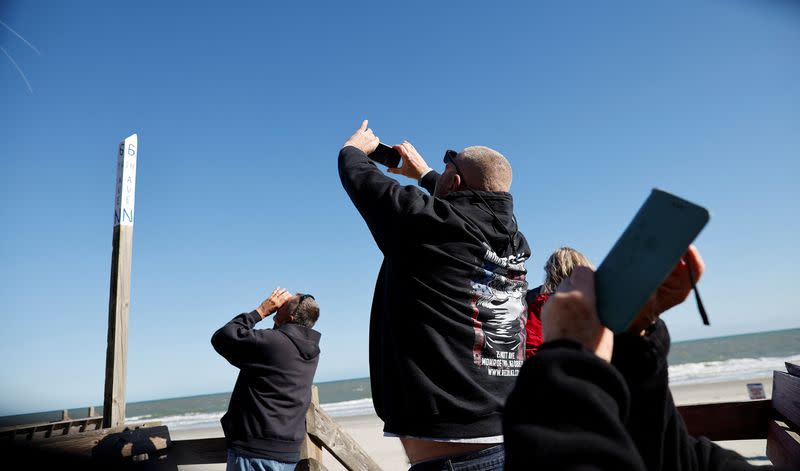 People photograph a suspected Chinese spy balloon as it floats off the coast in Surfside Beach