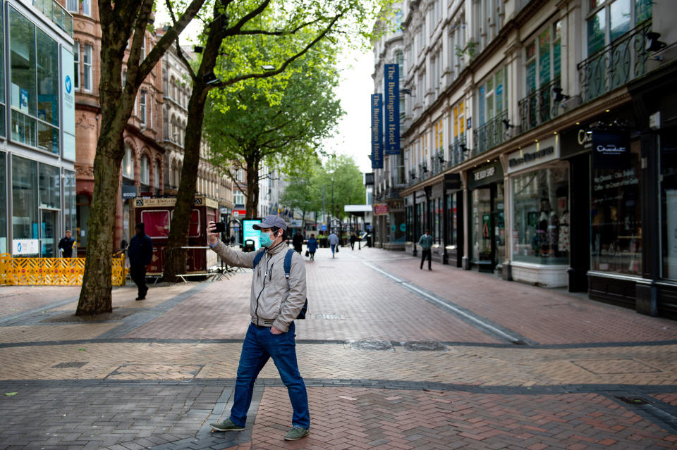 A pedestrian takes a photograph whilst walking on Hill Street in Birmingham city centre, as the UK continues in lockdown to help curb the spread of the coronavirus.