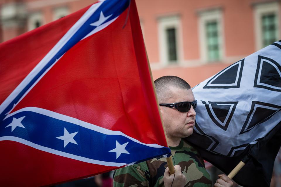 A far-right activist in Warsaw, Poland, holds a Confederate flag and a White Pride flag while taking part in a July 2015 demonstration against accepting over 2,000 immigrants to the country. (Photo: WOJTEK RADWANSKI via Getty Images)