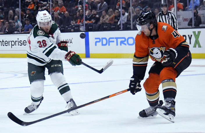 Minnesota Wild right wing Ryan Hartman (38) hits the puck past Anaheim Ducks defenseman Cam Fowler (4) during the first period of an NHL hockey game Friday, Oct. 15, 2021, in Anaheim, Calif. (AP Photo/John McCoy)