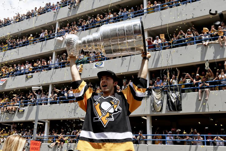 Pittsburgh Penguins' Kris Letang holds the Stanley Cup overhead along the victory parade route in Pittsburgh, Pa., June 15, 2016. The Penguins defeated the San Jose Sharks on Sunday to win the NHL hockey championship. (AP Photo/Keith Srakocic)