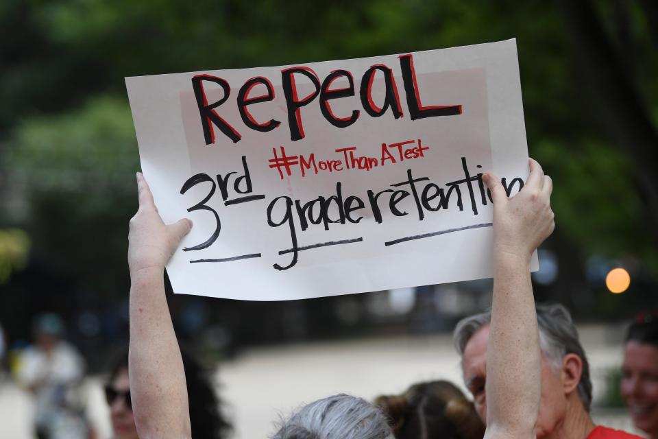 Amanda Collins holds up a sign while gathering with other education advocates at a rally against the Tennessee Comprehensive Assessment Program in Market Square on July 15.