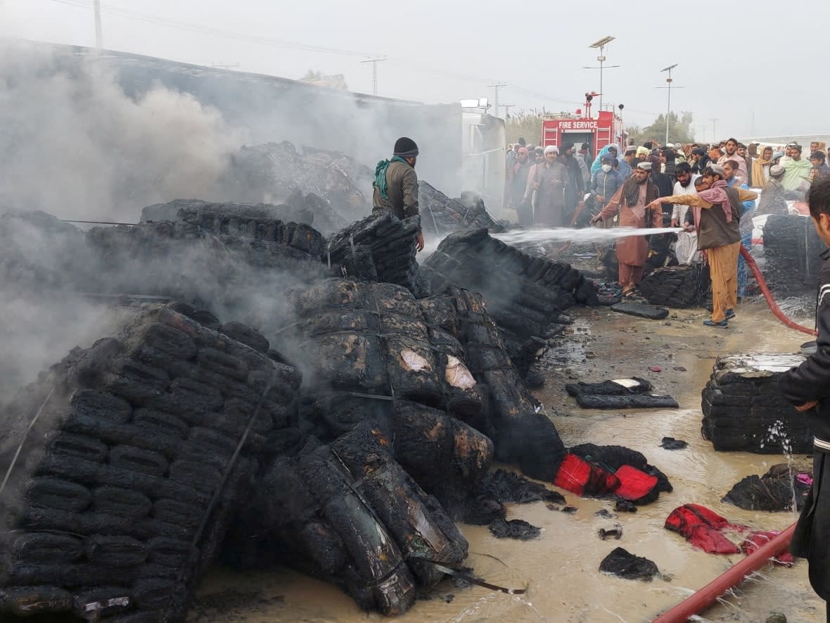 People douse a cargo supply truck after it was hit during artillery shelling in the Pakistan-Afghanistan border town of Chaman, Pakistan, on Dec. 11, 2022.  Amid a deteriorating relationship between the two countries, Pakistan has told the Canadian government it will not deport Afghans bound for this country.  (REUTERS - image credit)