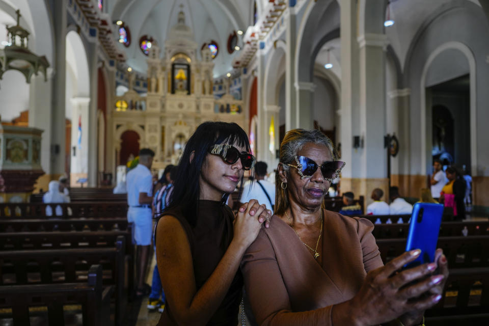 People take photos of themselves inside the shrine of the Virgin of Charity of El Cobre in El Cobre, Cuba, Sunday, Feb. 11, 2024. The Vatican-recognized Virgin, venerated by Catholics and followers of Afro-Cuban Santeria traditions, is at the heart of Cuban identity, uniting compatriots from the Communist-run Caribbean island to those who were exiled or emigrated to the U.S. (AP Photo/Ramon Espinosa)