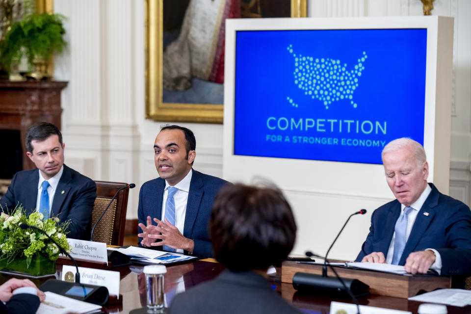 Consumer Financial Protection Bureau director Rohit Chopra, center, accompanied by President Joe Biden, right, and Transportation Secretary Pete Buttigieg, left, speaks at a meeting with his Competition Council on the economy and prices in the East Room of the White House in Washington, Wednesday, Feb. 1, 2023. (AP Photo/Andrew Harnik)