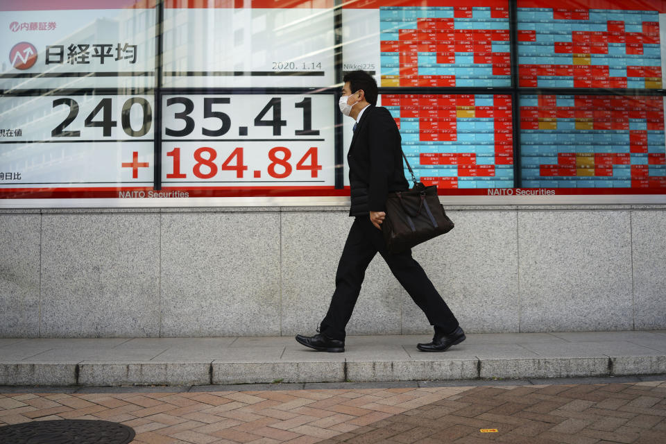 A man walks past an electronic stock board showing Japan's Nikkei 225 index at a securities firm in Tokyo Tuesday, Jan. 14, 2020. Asian shares followed Wall Street higher on Tuesday amid optimism that a trade deal between the U.S. and China will be a boon for the regional economy.(AP Photo/Eugene Hoshiko)