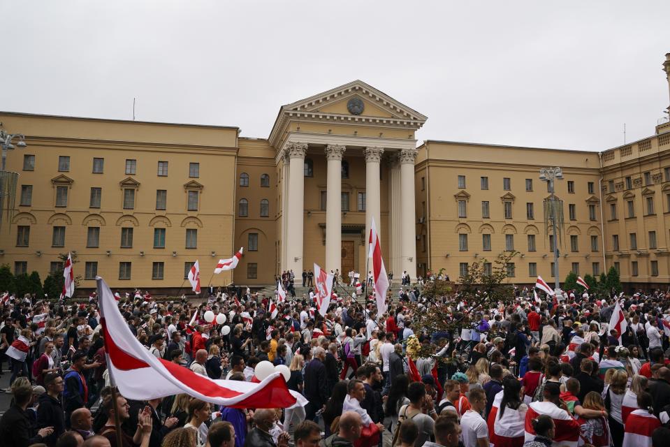 FILE - In this Aug. 23, 2020, file photo, protesters wave old national flags at a rally in front of the Belarusian KGB headquarters in Minsk, Belarus. Officers of the security agency have inundated factories warn workers that they could be fired or face criminal charges for organizing strikes to protest the reelection of authoritarian President Alexander Lukashenko. (AP Photo/Evgeniy Maloletka, File)
