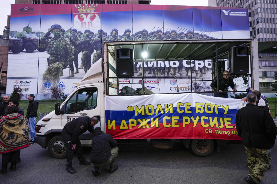 People set on a truck a Russian flag, that reads: "Pray to God, hold on to Russia", prior to a rally in front of the former Serbian army headquarters, destroyed during NATO's bombing campaign, in Belgrade, Serbia, Sunday, March 24, 2024. Serbia marks the 25th anniversary of the beginning of the NATO air-campaign in 1999, on Sunday. (AP Photo/Darko Vojinovic)