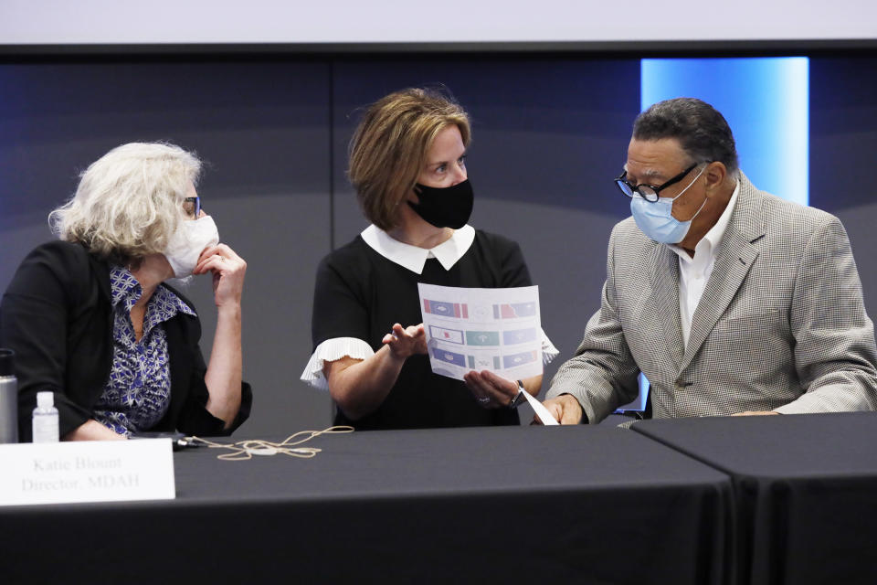 FILE - In this Aug. 18, 2020, file photo, Mississippi Department of Archives and History director Katie Blount, left, listens as liaison Holly Lange confers with Mississippi State Flag Commission chairman Reuben Anderson prior to the commissioners meeting to narrow down their finalists to five submitted flag designs at the Two Mississippi Museums in Jackson, Miss. After mothballing its old Confederate-themed state flag, Mississippi could choose a new one with a magnolia, a shield with wavy lines representing water, or an “edgy” representation of the Mississippi River snaking along the state’s western border. (AP Photo/Rogelio V. Solis, File)