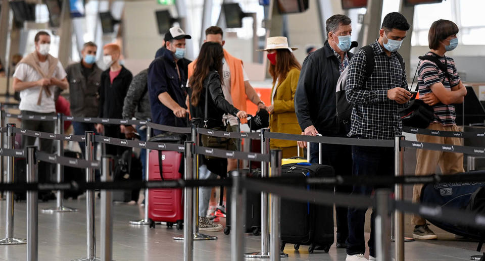 Line of people wearing masks at an airport.