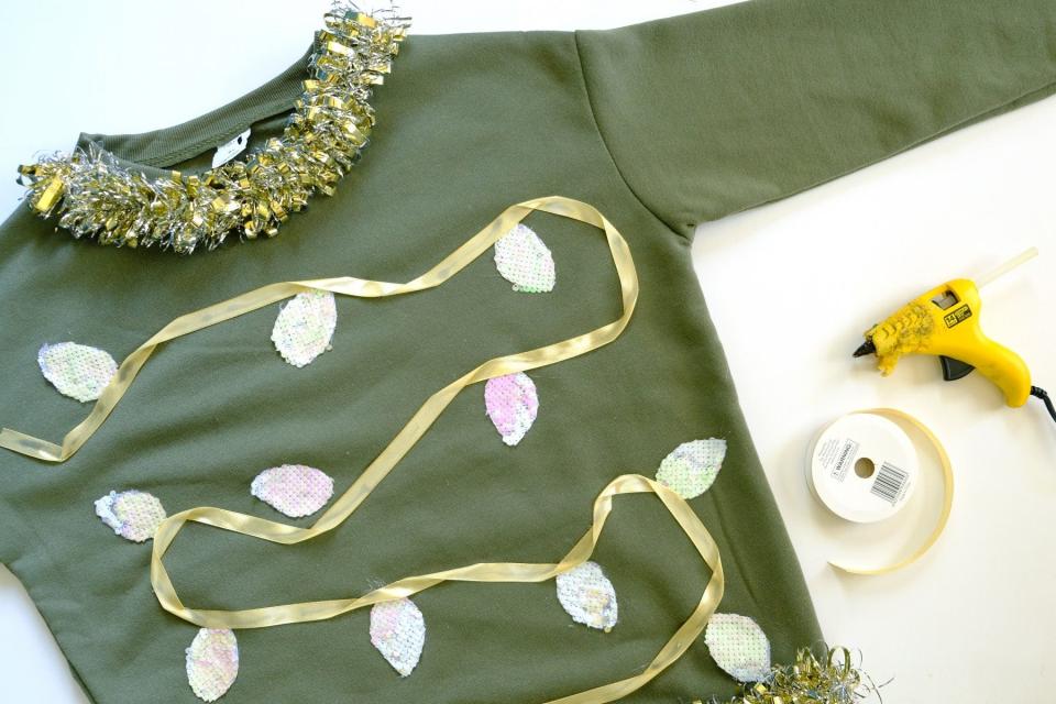 Use hot glue gun to attach ribbon to DIY holiday sweater.