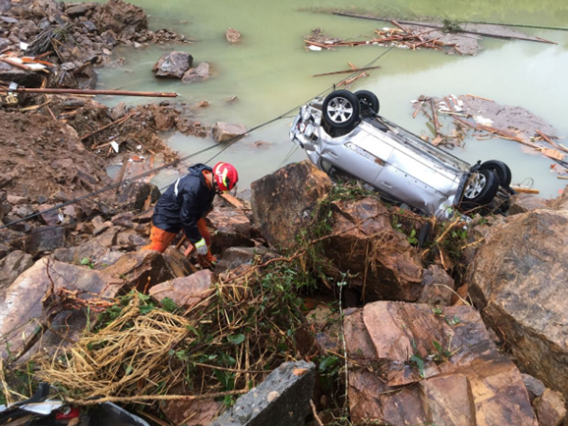 Ein Rettungshelfer neben einem überschlagenen Auto. Heftige Regenfälle durch den Taifun Megi führten zu einem Erdrutsch in Sucun Village, Lishui in der Zhejiang Provinz in China. (Bild: REUTERS/Stringer)