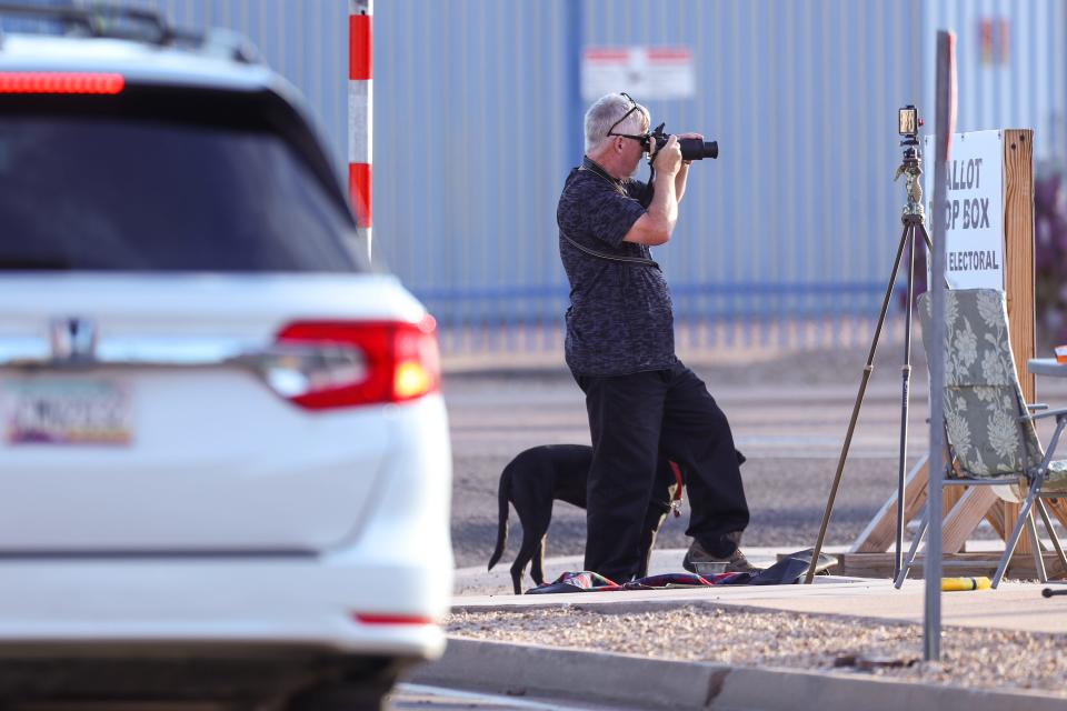A man takes photos of people exiting and entering the Maricopa County Tabulation and Elections Center on Oct. 19, 2022, in Phoenix.