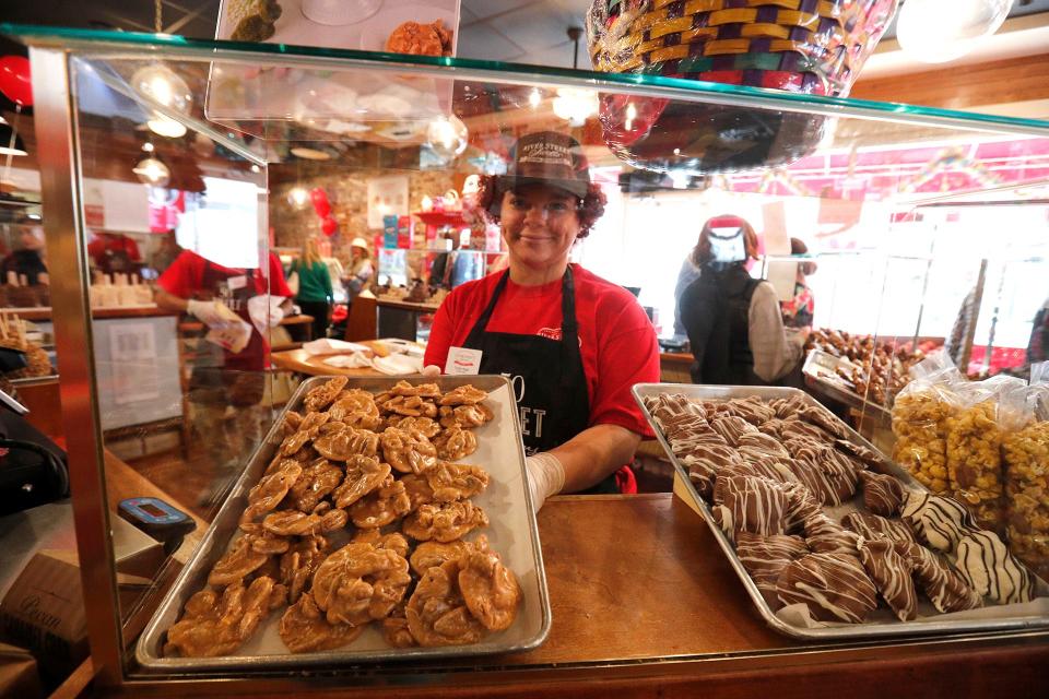 Trinity Nash slides a tray of pralines into the case inside the River Street Sweets location at 32 E. Broughton Street.