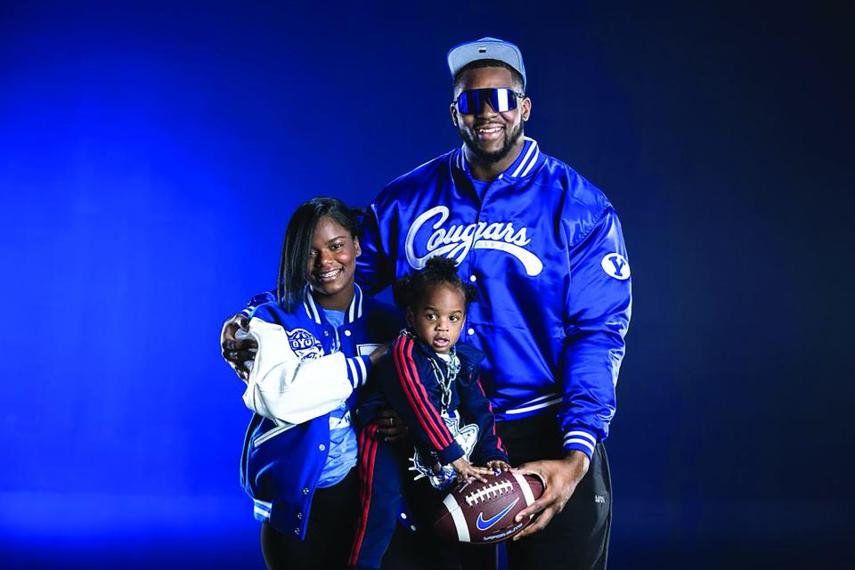 Caleb Etienne and Sataizha Buckner White pose with Caleb Jr. while donning their new BYU gear.