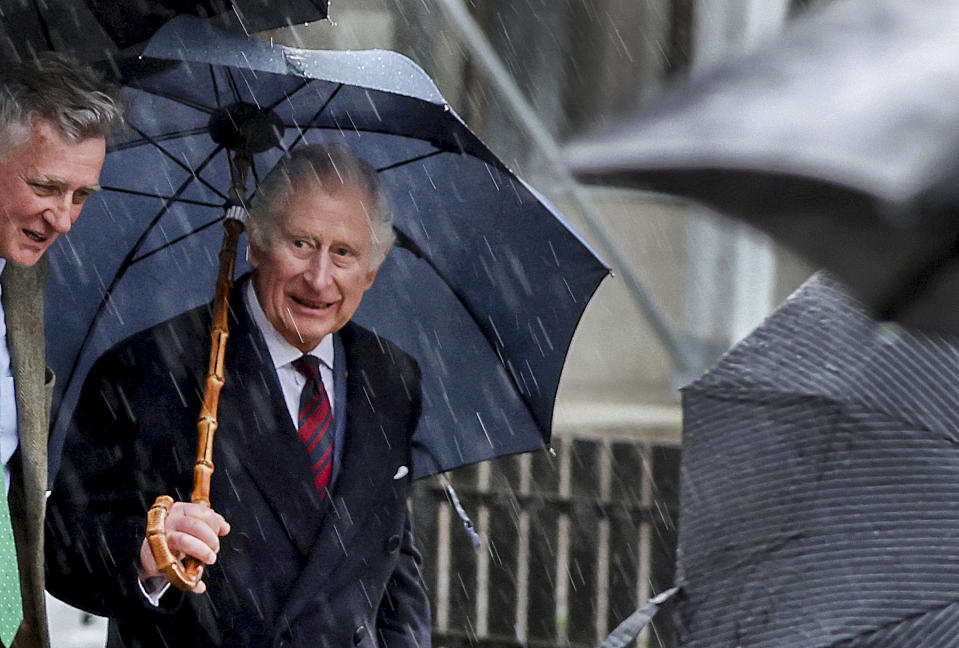 King Charles III of Great Britain, right, leaves the Brodowin ecovillage in the rain, Germany, Thursday, March 30, 2023. A heavy thunderstorm with lightning and thunder upset the strict protocol of the royal visit to the in Brandenburg. (Jens Buettner/DPA via AP, Pool)