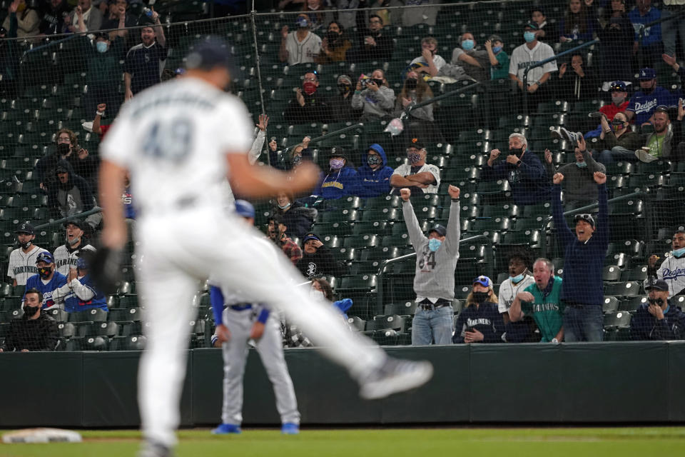 Fans in the stands cheer as Seattle Mariners relief pitcher Kendall Graveman (49) reacts after Mariners third baseman Dylan Moore caught a line drive hit by Los Angeles Dodgers' Will Smith to end the top of the seventh inning of a baseball game, Monday, April 19, 2021, in Seattle. (AP Photo/Ted S. Warren)