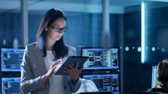 A woman studies data on a tablet.