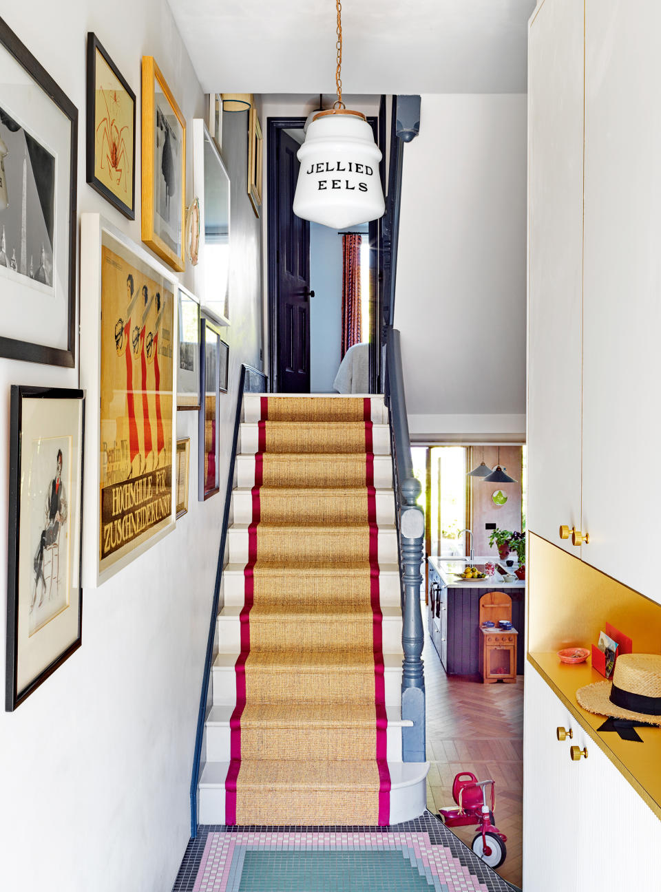 Narrow hallway painted white with gallery wall and runner