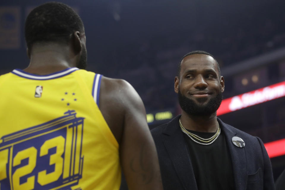 Injured Los Angeles Lakers forward LeBron James, right, smiles while talking with Golden State Warriors forward Draymond Green during the first half of an NBA basketball game in San Francisco, Thursday, Feb. 27, 2020. (AP Photo/Jeff Chiu)