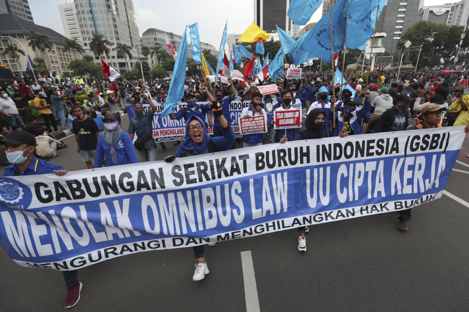 Protesters shout slogans during a march protesting against the new jobs law in Jakarta, Indonesia,Tuesday, Oct. 20, 2020. Protests against Indonesia's new jobs law were held in cities across the country on Tuesday, with demonstrators calling on the president to revoke the legislation they say will erode labor rights and weaken environmental protections. The banner held by the protesters reads: "Protest against the new Job Creation Law." (AP Photo/Achmad Ibrahim)