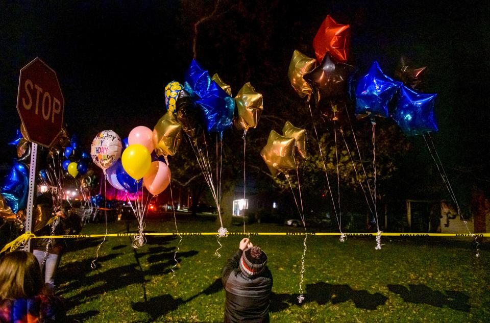 Well-wishers hang balloons on caution tape surrounding the area of a house fire that killed Madelynn McCain, 12, on November 24 in Creve Coeur. The balloons, many in her favorite colors, were part of a candlelight vigil held Saturday, Nov. 27, 2021 at the site.