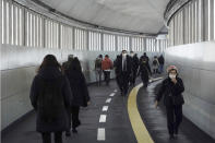 People wearing protective masks to help curb the spread of the coronavirus walk along an underpass Tuesday, Jan. 26, 2021, in Tokyo. The Japanese capital confirmed more than 1000 new coronavirus cases on Tuesday. (AP Photo/Eugene Hoshiko)