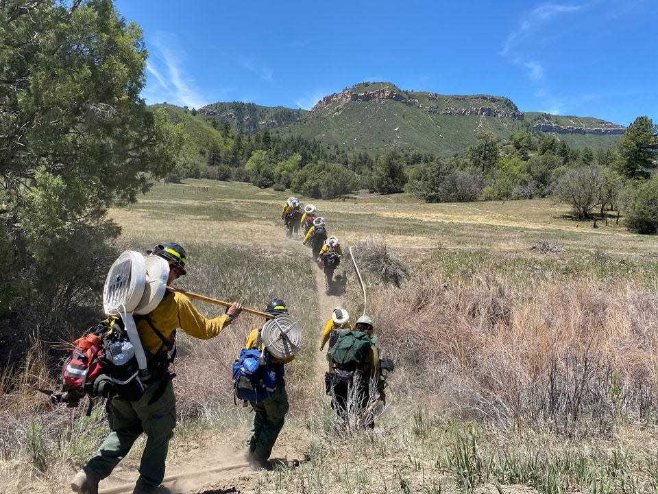 Engine crews hike in rolls of hose, plumbing the heel of the Perins Peak  Fire from the Perins Peak Trailhead.