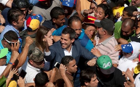 Venezuelan opposition leader Juan Guaido, center, who has declared himself the interim president of Venezuela, greets supporters as he arrives at a nationwide demonstration demanding the resignation of President Nicolas Maduro - Credit: AP