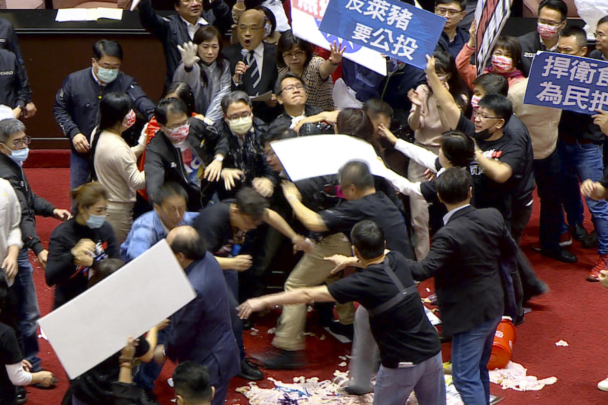 In this image made from video, lawmakers fight during a parliament session in Taipei, Taiwan, Friday, Nov. 27, 2020. Taiwan's lawmakers got into a fist fight and threw pig guts at each other Friday over a soon-to-be enacted policy that would allow imports of U.S. pork and beef. The banner at center top reads: “Protest against ractopamine pork, We want a referendum.” (FTV via AP)