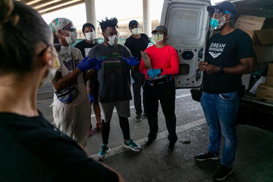 Armen Henderson, right, a University of Miami internist, works with a group of community volunteers to provide COVID-19 tests to the homeless in Miami’s Overtown neighborhood on Friday, March 27, 2020. Henderson also provided food and hand sanitizers. Another group, Showering Love, provided mobile showers and clothing.