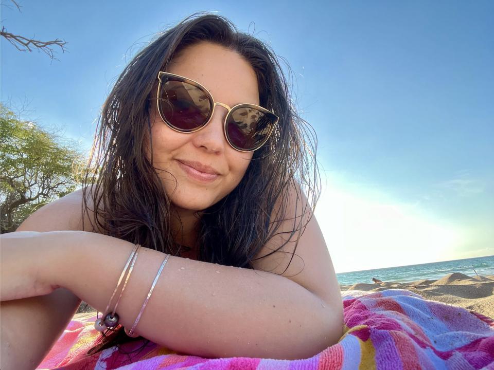 The writer wearing sunglasses lying on a towel on Hapuna Beach