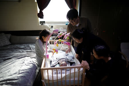 Lee Kyoung-min, a store manager at Lotte Mart and his wife Kim Mi-sung look at their baby son with their daughters at home in Seoul, South Korea, December 19, 2018. REUTERS/Kim Hong-Ji