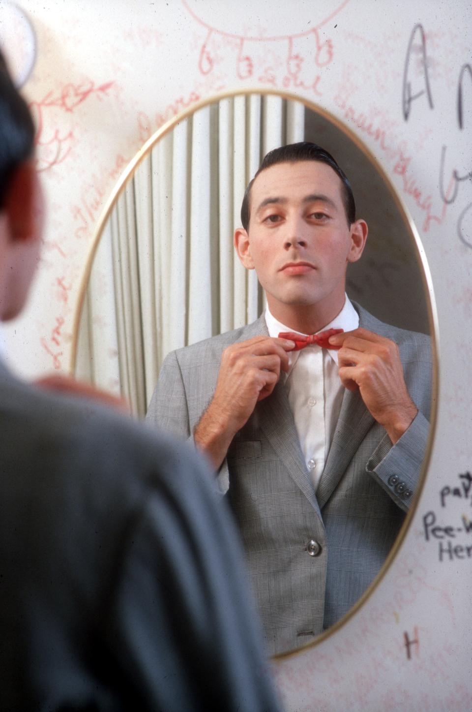 Paul Reubens dressed as Pee-wee Herman in a mirror