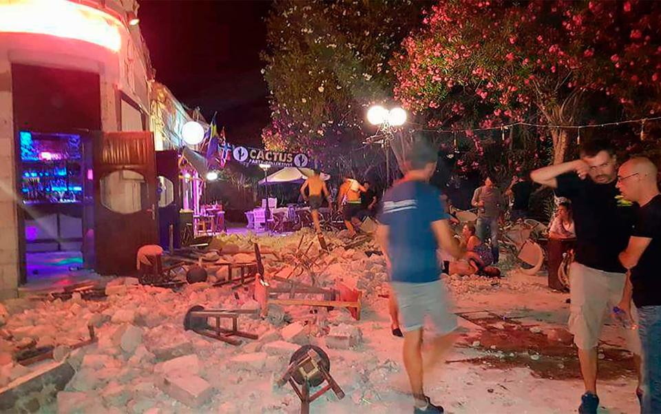 People stand outside damaged buildings - Credit: AFP/Getty