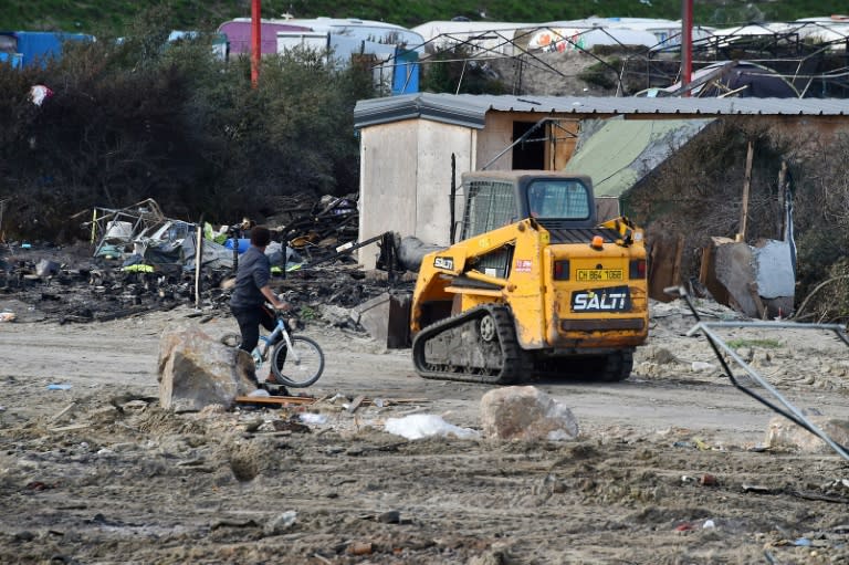 A young man on a bicycle stands near a bulldozer in the "Jungle" migrant camp in Calais, northern France, on October 27, 2016, during a massive operation to clear the squalid settlement where 6,000-8,000 people have been living in dire conditions