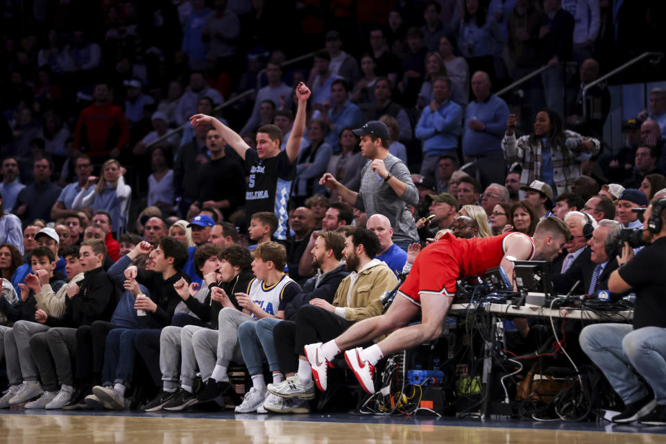 Ohio State guard Sean McNeil crashes into the scores table during the overtime of an NCAA college basketball game against North Carolina in the CBS Sports Classic, Saturday, Dec. 17, 2022, in New York. The Tar Heels won 89-84 in overtime. (AP Photo/Julia Nikhinson)