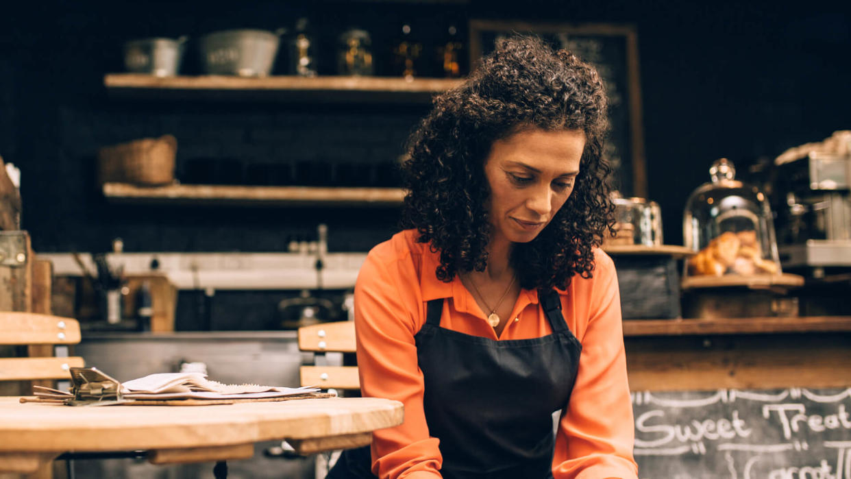 Shot of a mature woman using a mobile phone while working in a coffee shop.