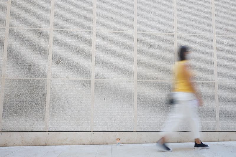 A woman walks past the Wall of Names at the Shoah Memorial in Paris