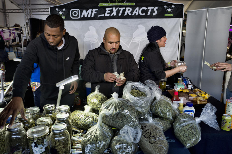 FILE - This Saturday, Dec. 29, 2018, file photo shows vendors from MF Extracts counting their intake of cash at their booth at Kushstock 6.5 festival in Adelanto Calif. The leading cannabis industry group in California announced Tuesday, Jan. 19, 2021, it had reached an agreement with a state credit union that will provide access to checking and other banking services for marijuana companies, ending what had been a longstanding obstacle for many businesses. (AP Photo/Richard Vogel, File)