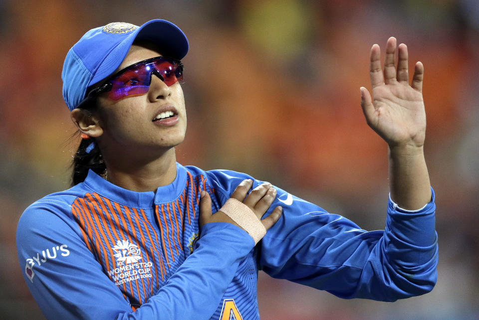 India's Smriti Mandhana leaves the field clutching her left shoulder after crashing into the signage while fielding against Australia in the Women's T20 Cricket World Cup in Sydney, Friday, Feb. 21, 2020. (AP Photo/Rick Rycroft)