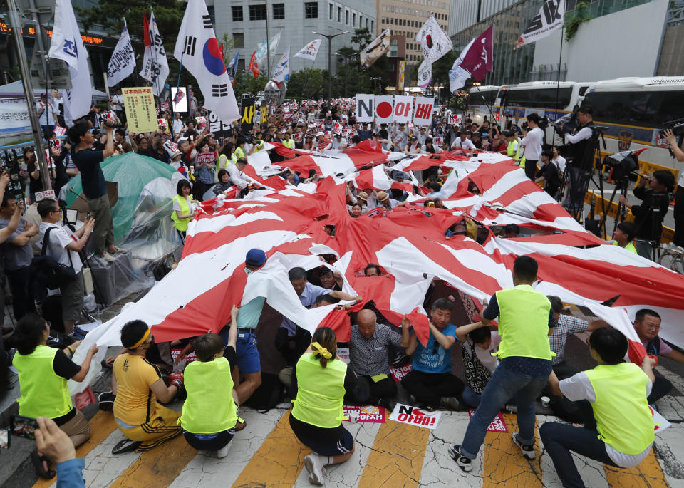 In this July 20, 2019, photo, protesters tear a Japanese rising sun flag during a rally denouncing the Japanese government's decision on their exports to South Korea in front of the Japanese embassy in Seoul, South Korea. South Korea has threatened to end a military intelligence sharing agreement with Japan as their tensions escalate over export controls. The agreement, known as GSOMIA, is a symbol of the countries’ trilateral security cooperation with their ally United States in the region. (AP Photo/Ahn Young-joon)