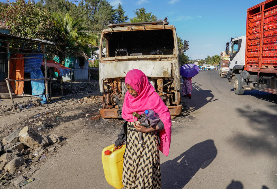 A woman walks past the wreckage of a damaged vehicle on the main road in the city of Haik, Ethiopia, January 12, 2022 just south of the embattled Tigray region. / Credit: J. Countess/Getty