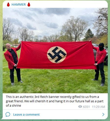 A screenshot of a photo posted to the Telegram feed of Christopher Pohlhaus aka "Hammer." Pohlhaus, left, and another Blood Tribe member, hold a flag that was flown in Nazi-Germany. The Blood Tribe, originally based in Maine, claims to have launched an Ohio chapter.