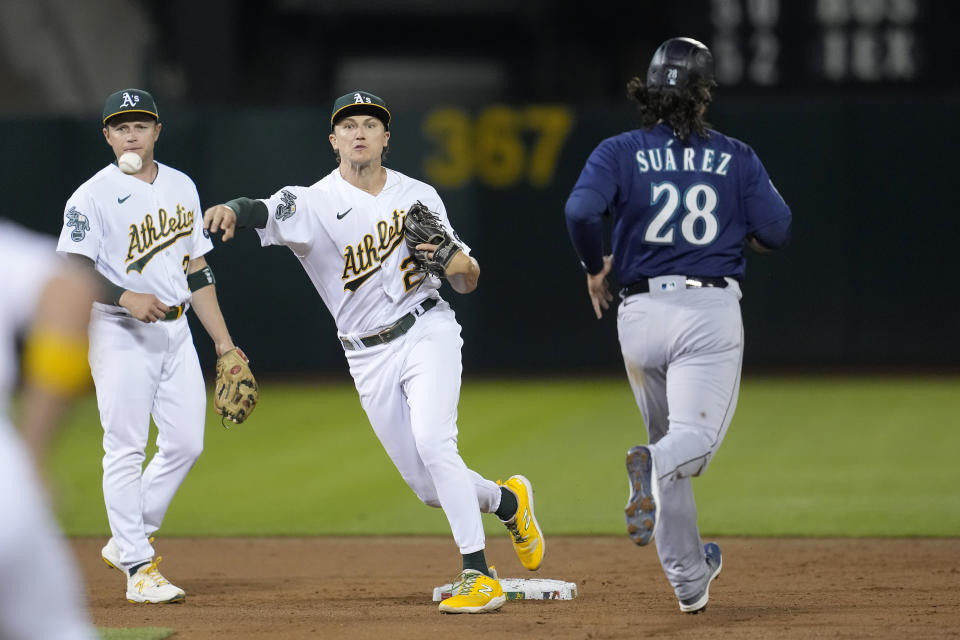 Oakland Athletics second baseman Zack Gelof, center, throws to first base after forcing out Seattle Mariners' Eugenio Suarez (28) at second on a double play hit into by Ty France during the second inning of a baseball game in Oakland, Calif., Monday, Sept. 18, 2023. (AP Photo/Jeff Chiu)