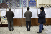 Voters check the lists of the candidates in the parliamentary elections at a polling station in Tehran, Iran, Friday, Feb. 21, 2020. Iranians began voting for a new parliament Friday, with turnout seen as a key measure of support for Iran's leadership as sanctions weigh on the economy and isolate the country diplomatically. (AP Photo/Vahid Salemi)