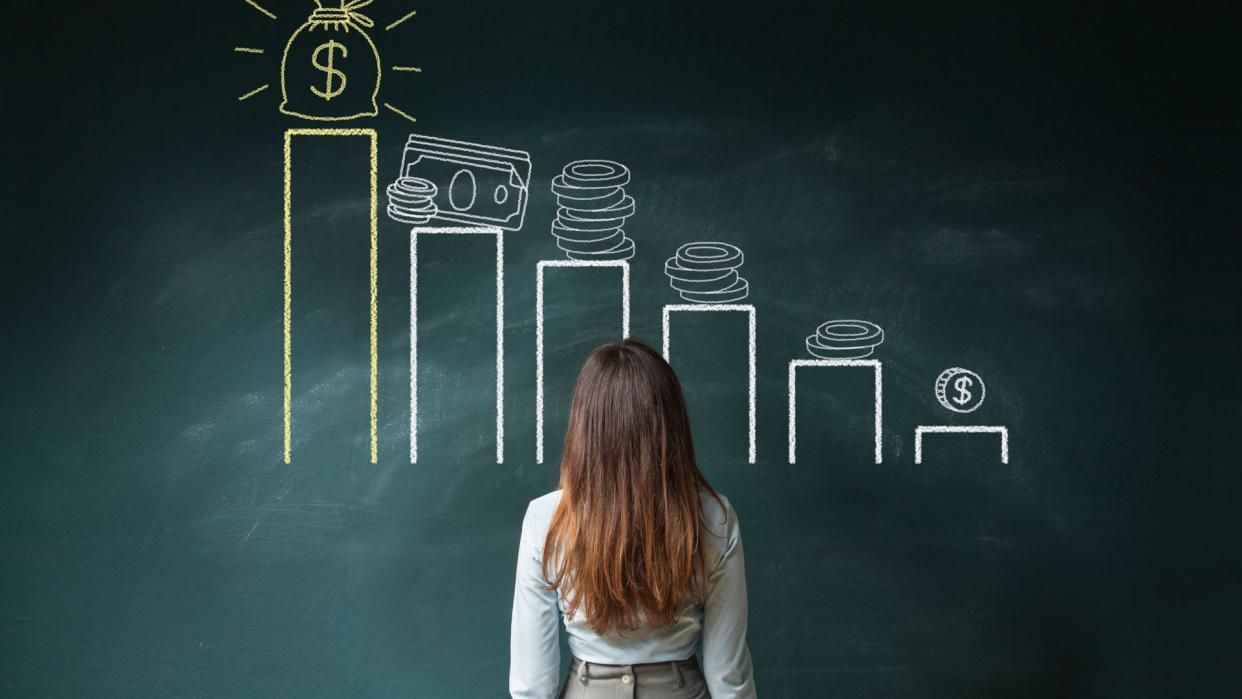 Business woman standing in front of a blackboard with a financial chart.