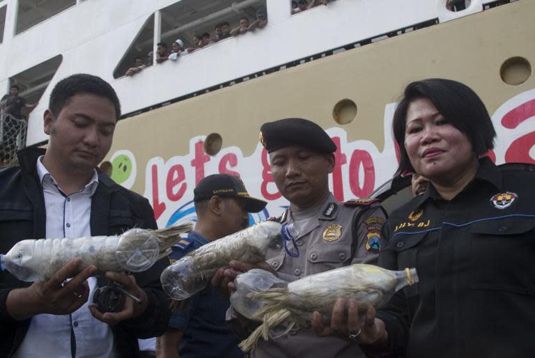 Police and customs officials hold rare Indonesian yellow-crested cockatoos, jammed inside plastic water bottles, confiscated from an alleged wildlife smuggler, on May 4, 2015